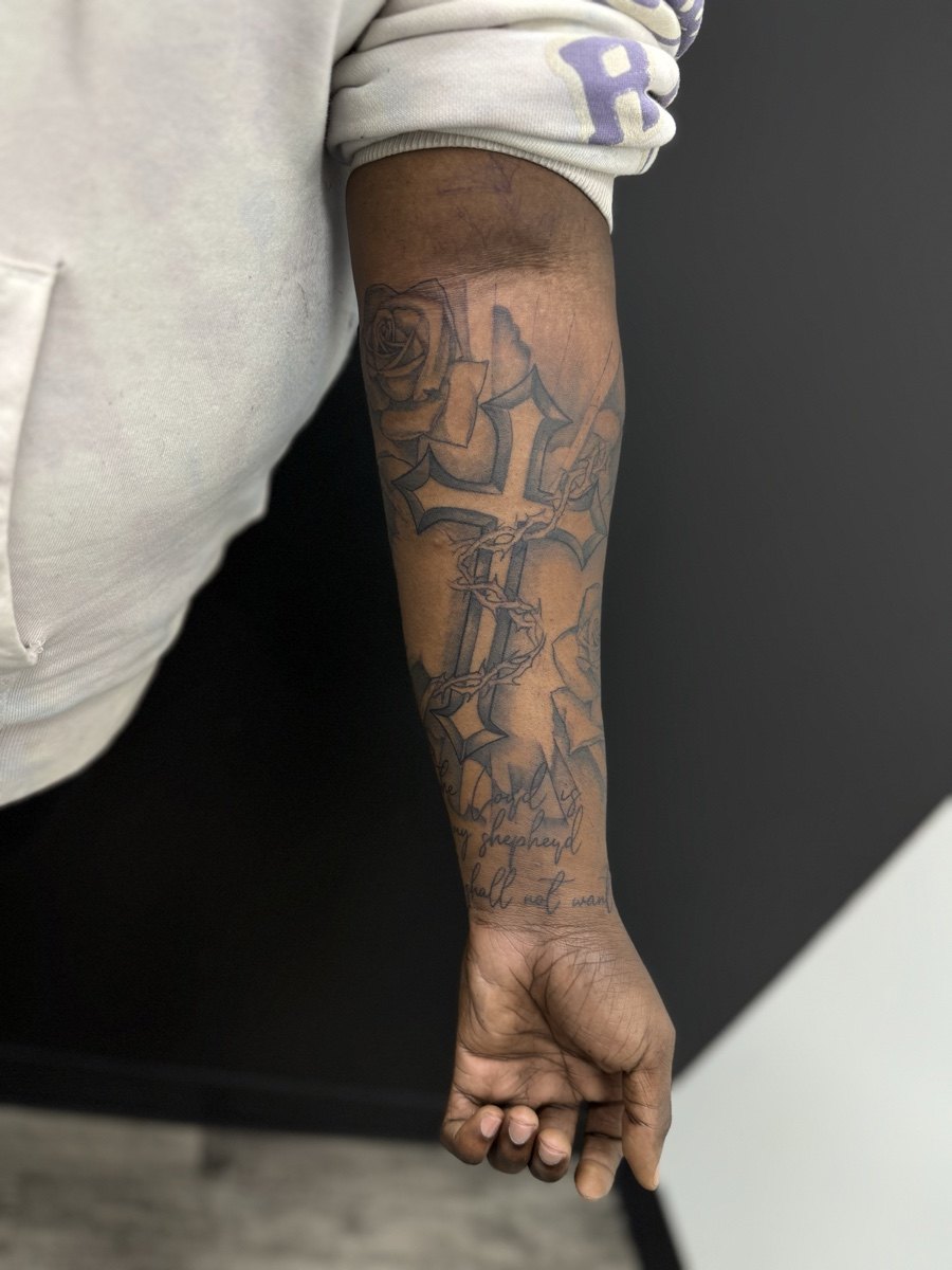 Layered black and grey tattoo covering a forearm.