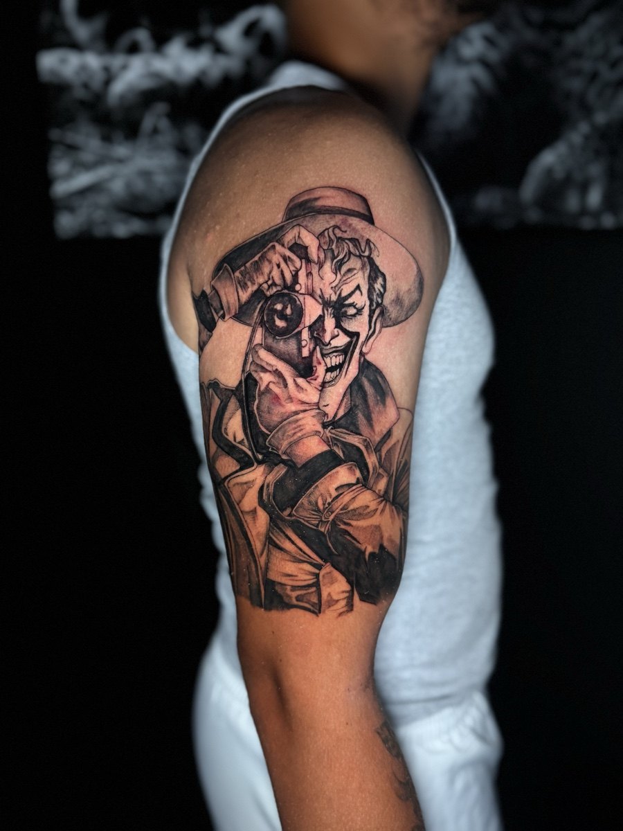 Black and grey portrait composition tattooed on an upper arm.