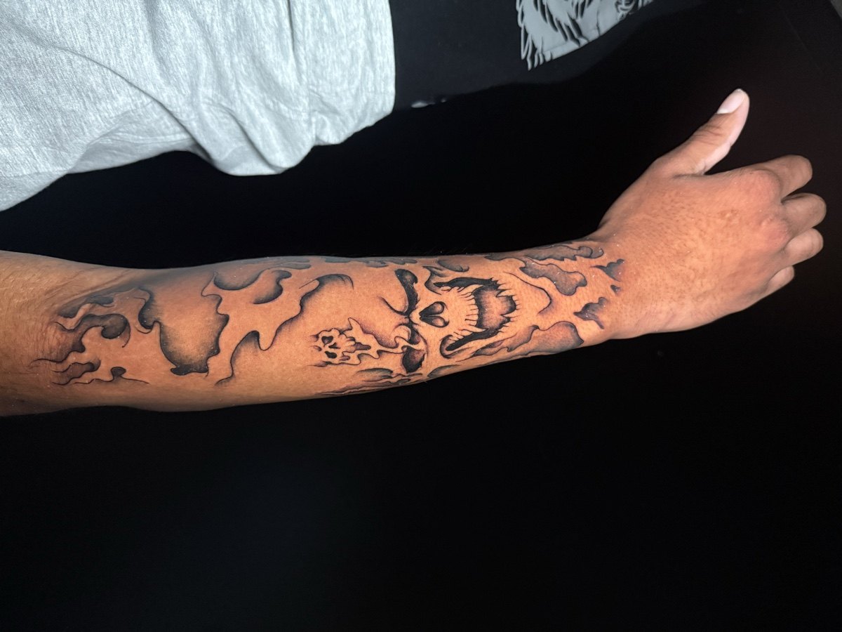 Black and grey landscape tattoo running along a forearm.