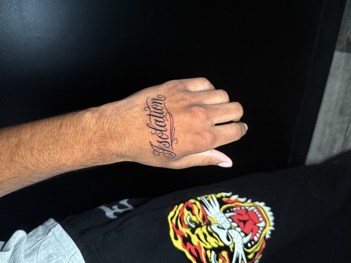 Small script lettering tattoo across a hand.