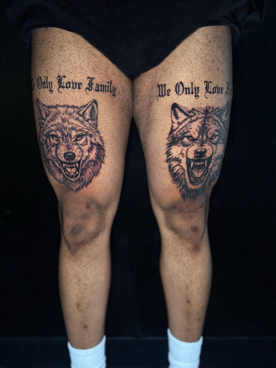 Paired black and grey illustrative tattoos above the knees.