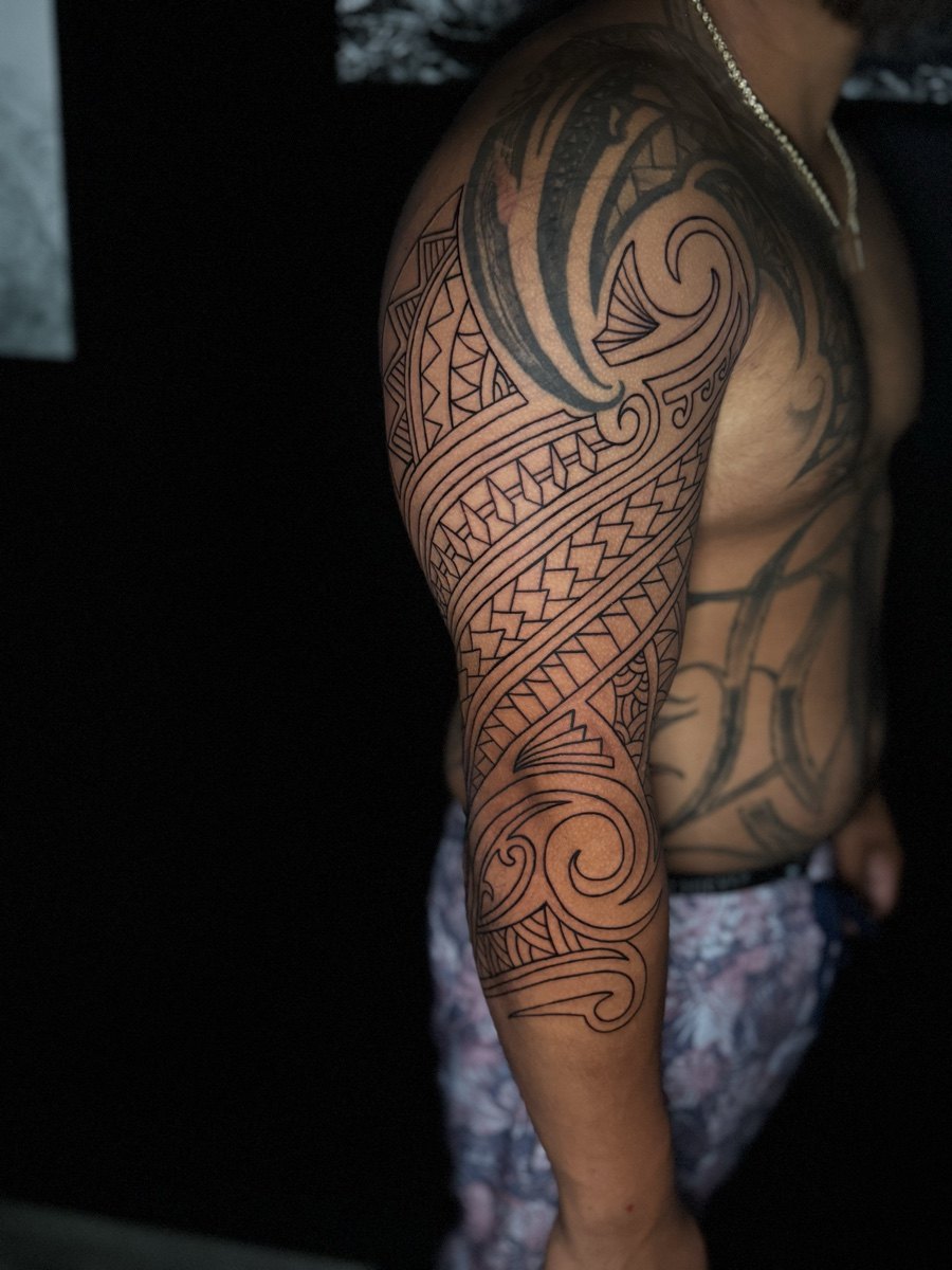 Large ornamental blackwork tattoo across a shoulder and upper arm.